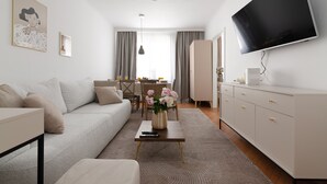 A modern living room with a sofa, coffee table, TV, and a dining area with a table and chairs.