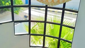 A spiral staircase with a view of a lush green garden through large windows. - Villa Mar Azul (Manta)