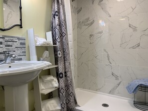 Regadera, secadora de cabello, toallas, papel de baño 