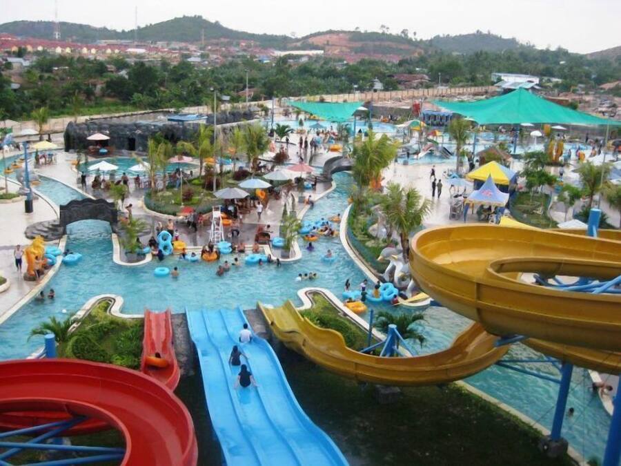 A water park with multiple slides, pools, and a mountainous backdrop.