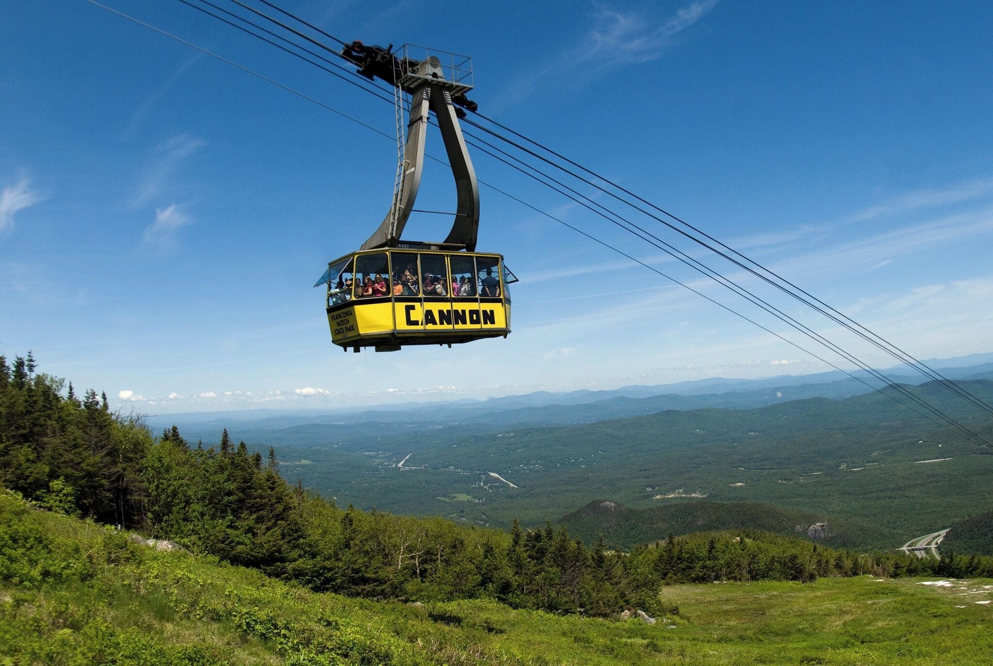 A cable car labeled "Cannon" suspended over a mountainous landscape.