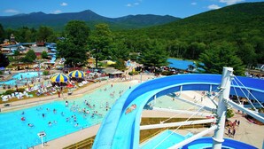 A water park with a large pool, slides, and a mountainous backdrop. - Parkers Motel (Lincoln)