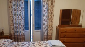 Une chambre à coucher avec un lit, une commode, un miroir et une porte avec des rideaux.