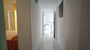A narrow hallway with a bed on the left, a door at the end, and a bathroom visible through an open door. - SE019 - Senigallia, delightful townhouse with portico (Senigallia)