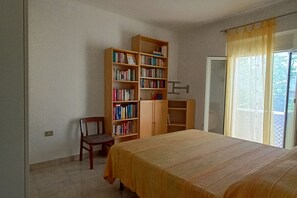 Een slaapkamer met een bed, een houten boekenkast, een stoel en een raam met gordijnen.