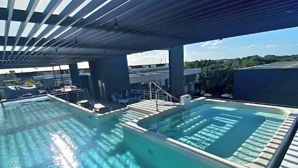 Ein Pool auf dem Dach mit klarem Wasser, eine überdachte Sitzgelegenheit und Blick auf die umliegende Landschaft.