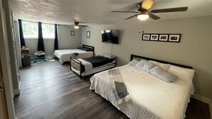 A hotel room with two beds, a ceiling fan, a TV, and a window with curtains. - A W🌊VE From It All! Secure boat storage, huge yard, lots of outdoor games! (Page)