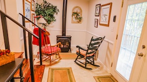 A cozy living room with a fireplace, rocking chairs, and a staircase.