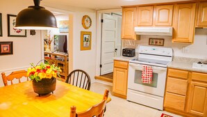 A kitchen with wooden cabinets, a stove, and a dining table with chairs.