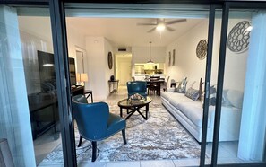 A living room with a blue armchair, a white sofa, and a dining area with a table and chairs. - Awesome Apartment near the Beach (Naples)