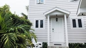A white two-story house with a front porch, a small garden with a palm tree, and a gravel pathway leading to the door. - Oasis on Poitier in Nassau Bahamas - your private retreat. (Nassau)
