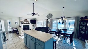 Una cocina amplia con una isla central, un comedor con una mesa grande y una chimenea.
