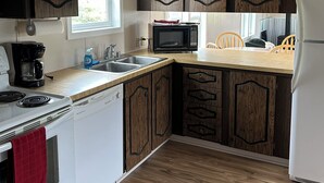 A kitchen with wooden cabinets, a microwave, a stove, a dishwasher, and a refrigerator. - Cozy Quiet Home on Sage Creek (Dell)