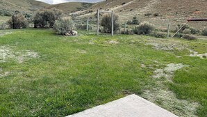 A grassy field with a concrete structure, a fence, and a hill in the background. - Cozy Quiet Home on Sage Creek (Dell)