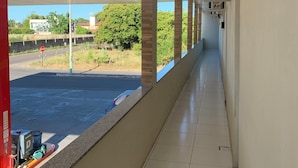 A corridor with a view of a parking lot and greenery outside. - Suite rooms in Pousada Jesus me Deu in Iguatu/Ce, 200m from the Airport. (Bugi Iguatu)