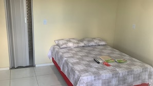 A single bed with a patterned bedspread and pillows, a remote control, and a green object on the bed. - Suite rooms in Pousada Jesus me Deu in Iguatu/Ce, 200m from the Airport. (Bugi Iguatu)