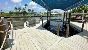 A wooden dock with benches, a covered area, and a waterway with boats. - Island Cottage in Quaint Matlacha Florida. Amazing island life is a click away… (Matlacha)