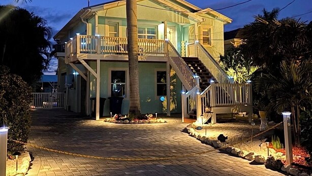A two-story house with a balcony, a staircase, and a paved driveway. - Island Cottage in Quaint Matlacha Florida. Amazing island life is a click away… (Matlacha)