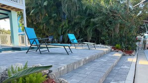Un espace aménagé au bord de la piscine, avec des chaises longues et un chemin en pierre.