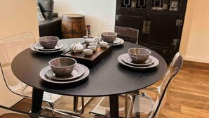 Une table ronde où sont disposés quatre bols et une théière, le tout posé sur un plateau en bois foncé.