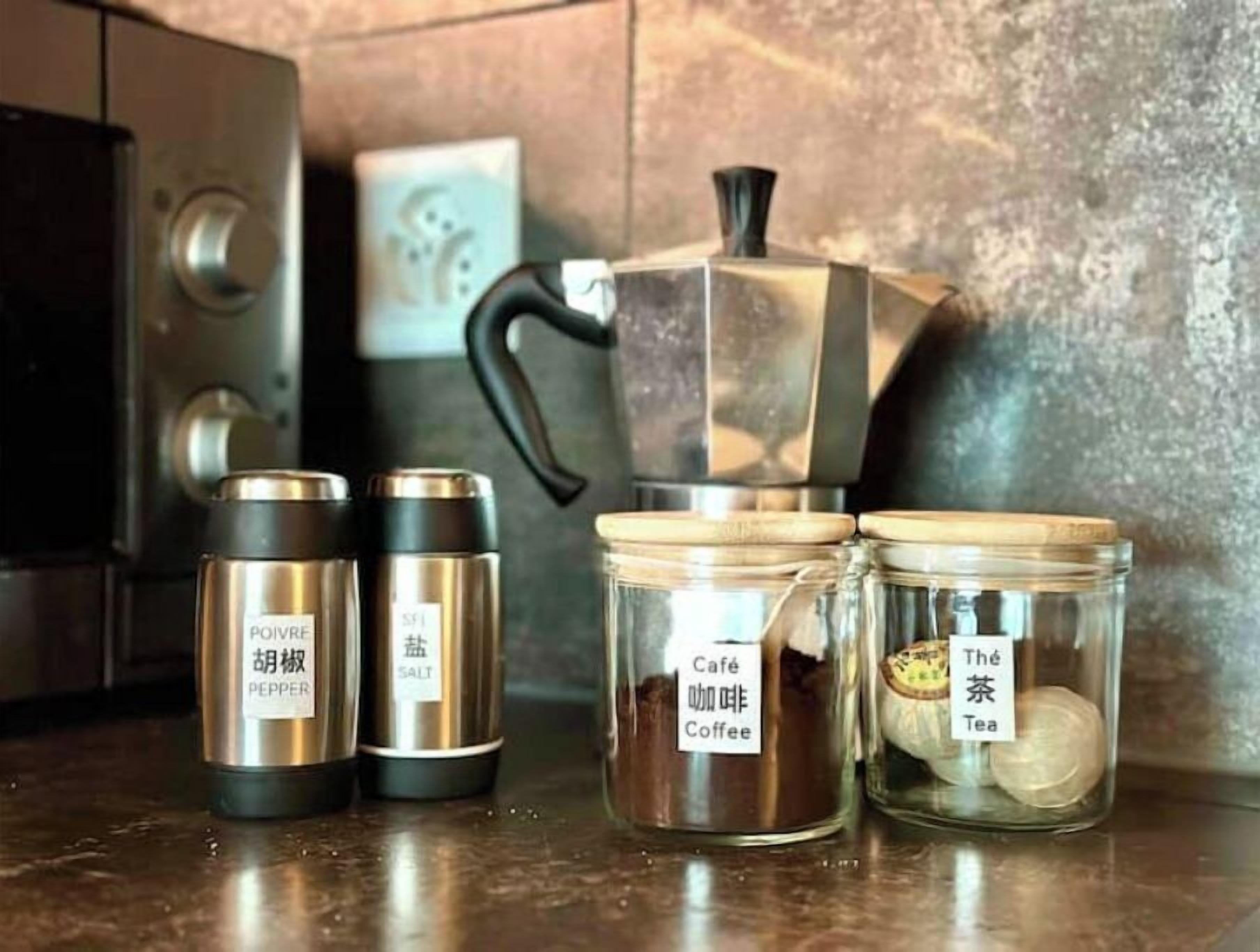 A kitchen counter with a coffee maker, pepper and salt containers, and jars labeled 'Café Coffee' and 'The Tea'.
