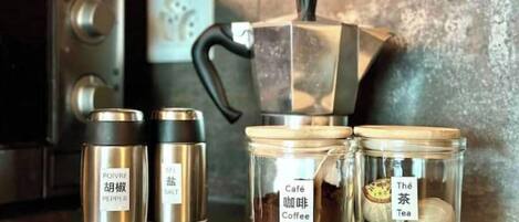 A kitchen counter with a coffee maker, pepper and salt containers, and jars labeled 'Café Coffee' and 'The Tea'.