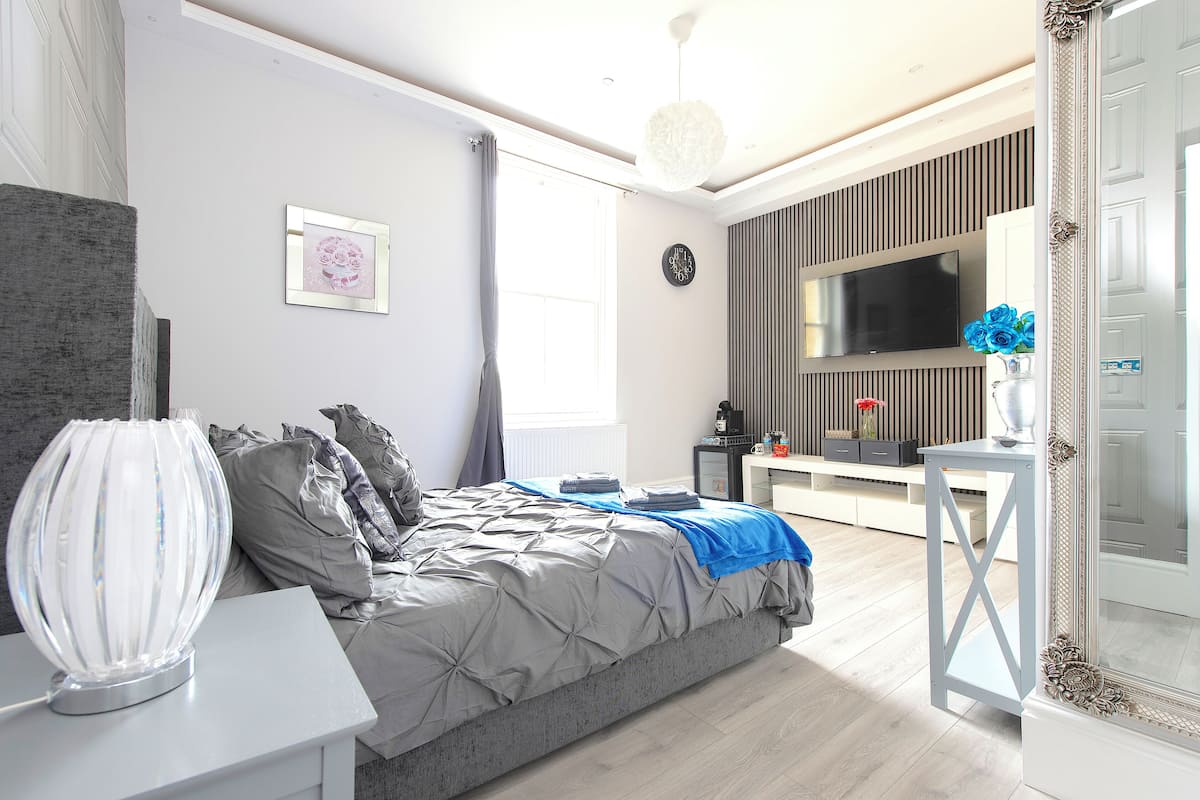 A modern bedroom with a bed, bedside table, and a TV.