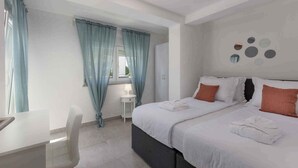 A hotel room with a bed, a desk, and a chair. There is a window with curtains, a bedside table, and a wall with circular decorations. - Holiday apartment with pool (Dramalj)