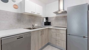 A modern kitchen with white cabinets, a stainless steel refrigerator, a microwave, and a dishwasher. - Holiday apartment with pool (Dramalj)