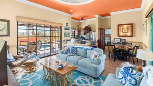 A spacious living room with a large gray sofa, a wooden coffee table, and a dining area with a table and chairs.