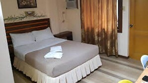 Un dormitorio con cama, mesita de noche, aire acondicionado instalado en la pared y una puerta.