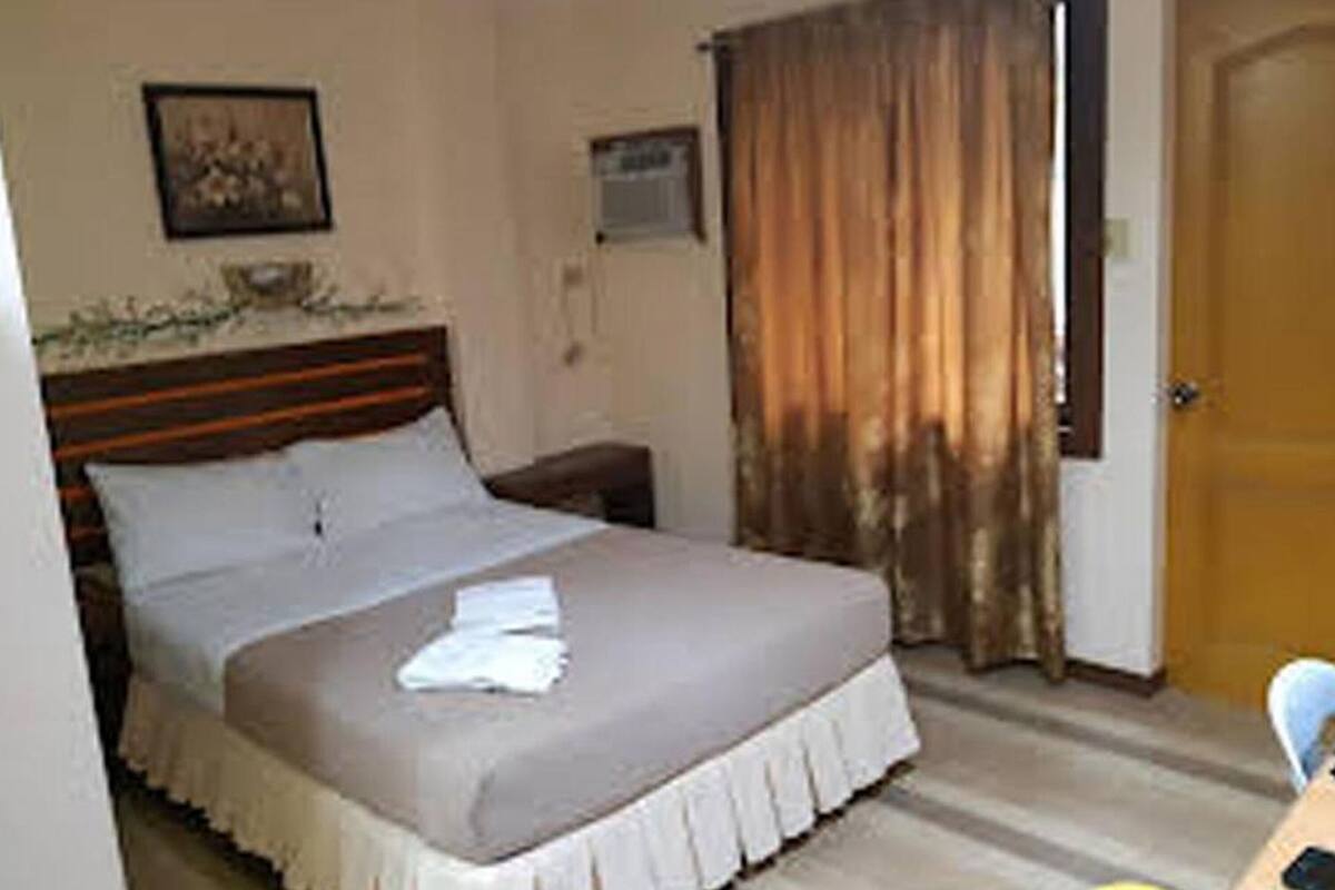 A bedroom with a bed, a nightstand, a wall-mounted air conditioning unit, and a door.