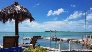 A beachside lounge with a thatched umbrella, lounge chairs, and a small pool area. - Sunset Wishes on Bone Fish Flats (Hermitage)