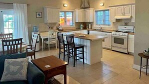 A spacious kitchen with a central island, a dining area with chairs, and a ceiling fan. - Sunset Wishes on Bone Fish Flats (Hermitage)