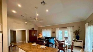 A spacious kitchen with a large island, dining area with chairs, and a ceiling fan. - Sunset Wishes on Bone Fish Flats (Hermitage)