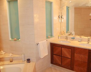 Un baño con dos lavamanos, una bañera y un espejo grande.