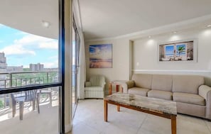 Una sala de estar con un sofá, una mesa de centro, una silla y un cuadro en la pared.
