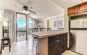A modern kitchen with a central island, a refrigerator, and a ceiling fan.