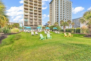 A hotel courtyard with multiple lounge chairs, a pool area, and tall buildings in the background.