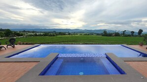 Una piscina rectangular con borde de azulejos, rodeada por una cubierta de madera.