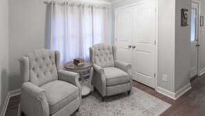A room with two armchairs, a small round table, and a patterned rug. There is a white door and a window with curtains. - Countryside Retreat (Soddy-Daisy)