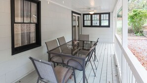 A covered porch with a glass table and chairs, white walls, and a view of the outdoors. - Countryside Retreat (Soddy-Daisy)