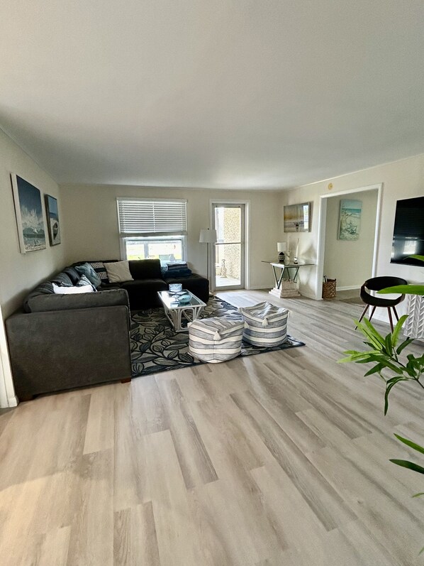 A modern living room with a sofa, ottomans, a coffee table, and a TV. - Ocean Breeze House - Summer fun Sleeps 8 boating, fishing and 🦞 Lobster season. (Summerland Key)