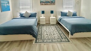 Ein Schlafzimmer mit zwei Betten, einem Deckenventilator und einem Teppich.
