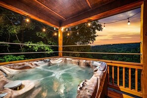 Un bain à remous avec une terrasse en bois et vue sur la forêt.
