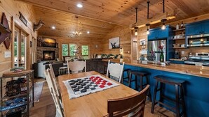Un acogedor interior de cabaña con una mesa de comedor de madera, una zona de bar y una chimenea.
