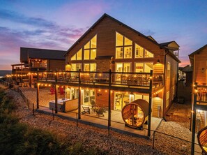 A two-story building with a balcony, outdoor seating area, and a circular wooden structure.
