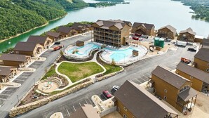 Vue aérienne d’un quartier résidentiel avec une piscine, un parking et un lac en arrière-plan.