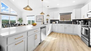 Une cuisine moderne avec des meubles blancs, un grand îlot central et des luminaires suspendus.