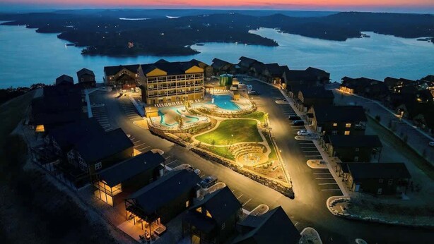 Une vue aérienne d’un complexe hôtelier comprenant une piscine, plusieurs bâtiments et un accès au bord de l’eau.